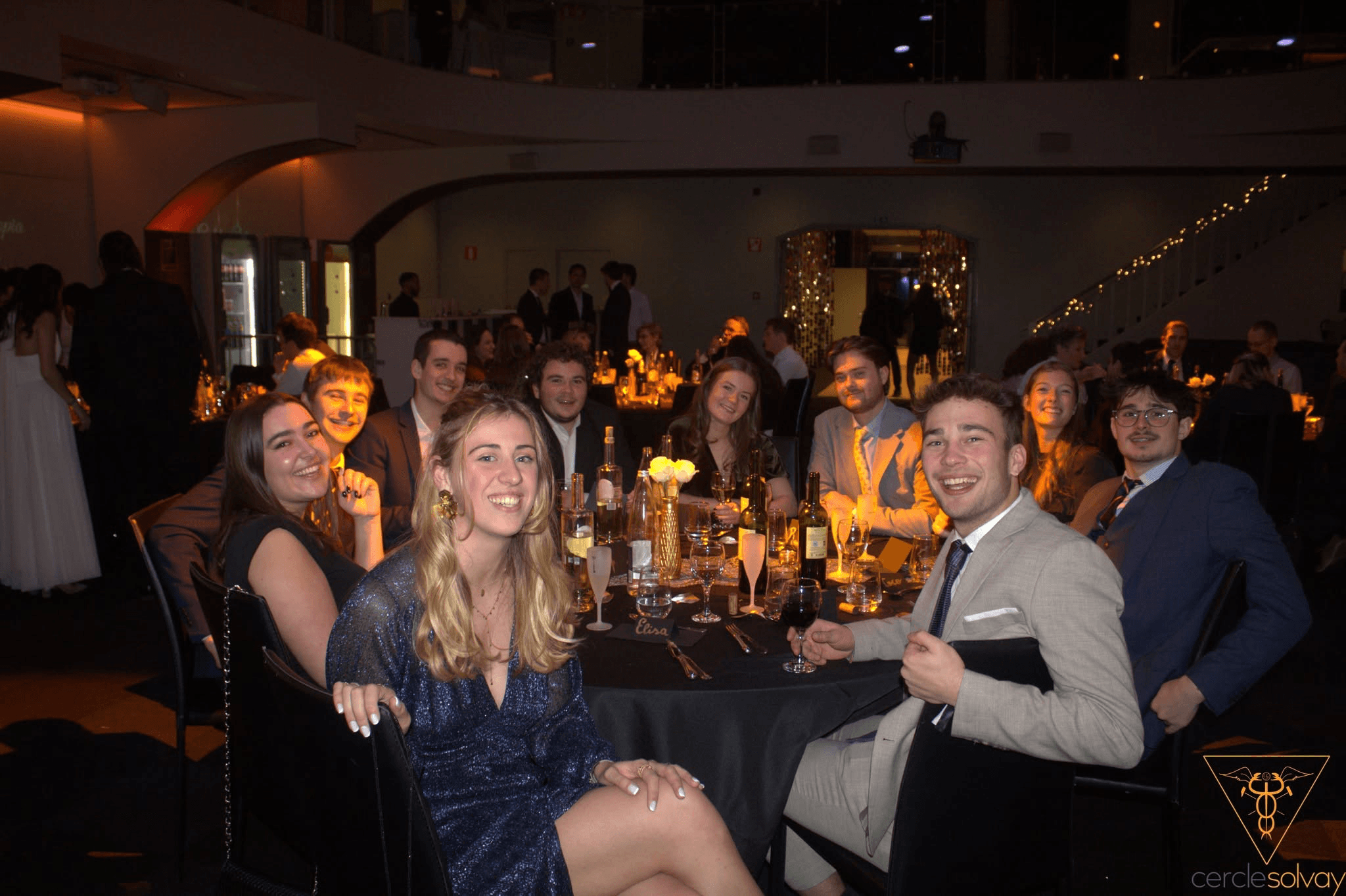 Convives en tenue de soirée souriant autour d'une table du banquet