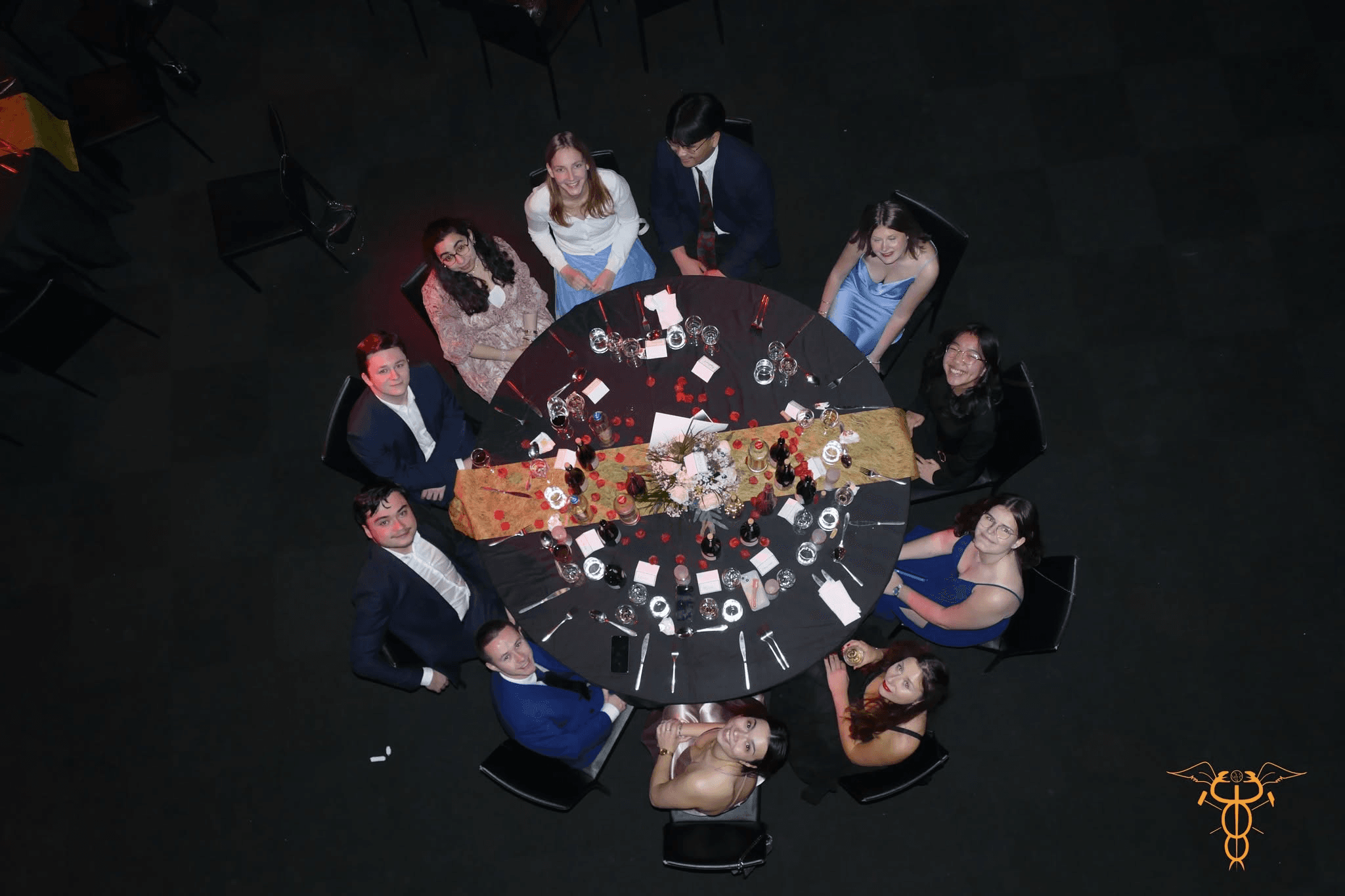 Table ronde du banquet vue du dessus, les convives levant les yeux vers l'objectif