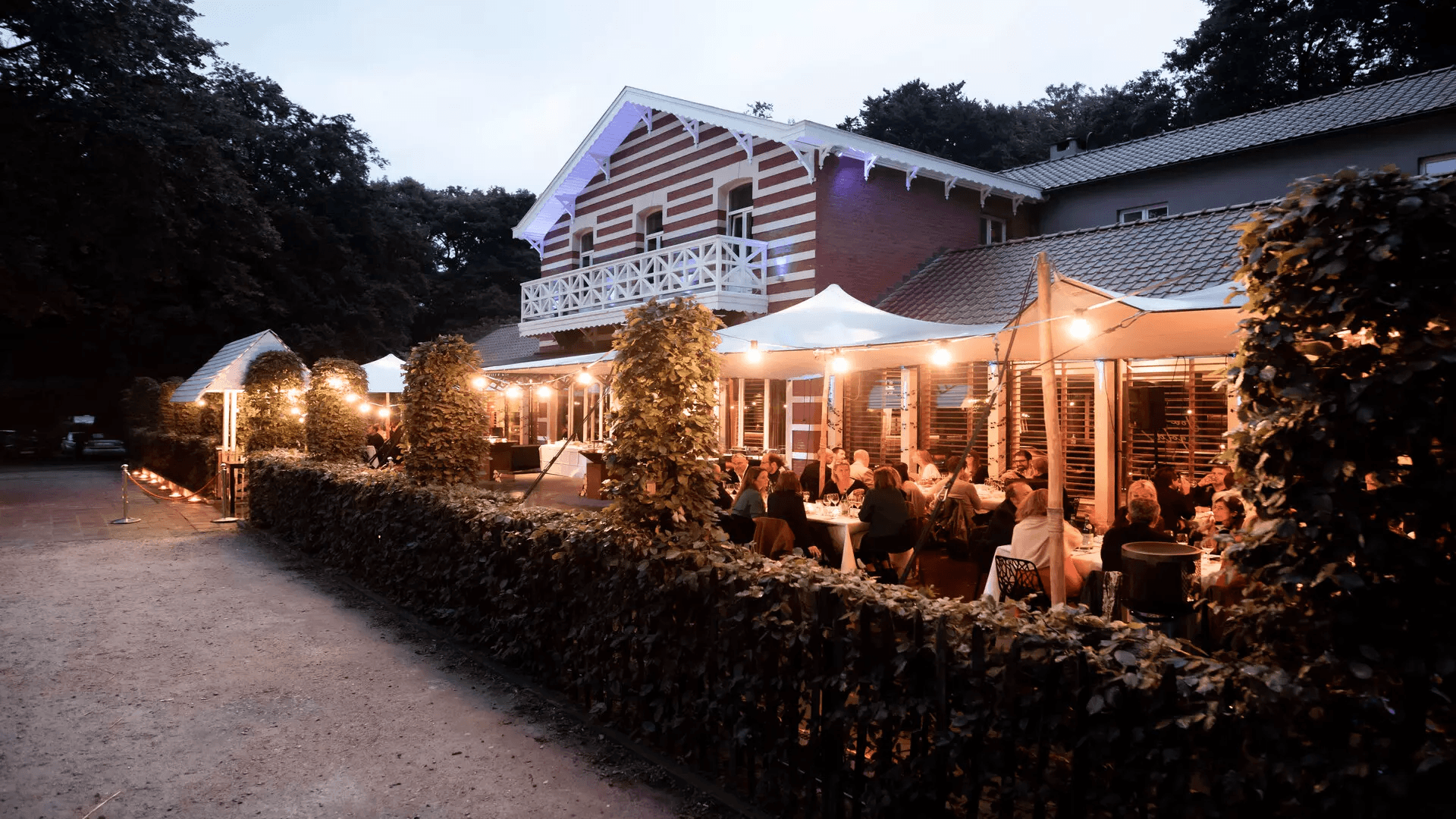 Terrasse des Jeux d'Hiver à la tombée du jour, tables dressées sous les guirlandes lumineuses